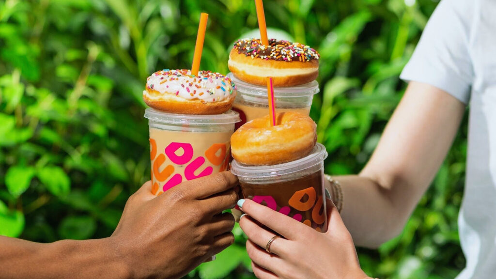 three people holding Dunkin Donuts super bowl free coffee cups